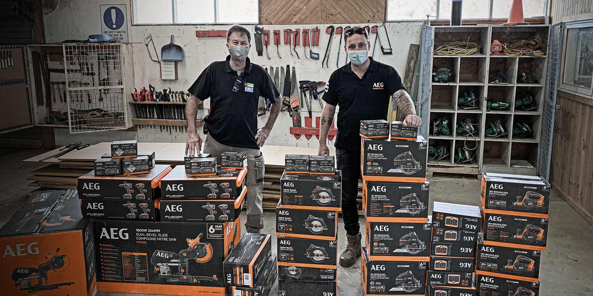 An AEG Onsite rep and a trades person stand behind a tall stack of AEG powertools